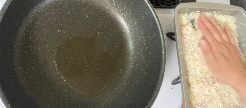 7. フライパンにサラダ油大さじ2を入れ、中火で熱する。鶏むね肉にパン粉をギュッと押しつけてからフライパンに乗せる。