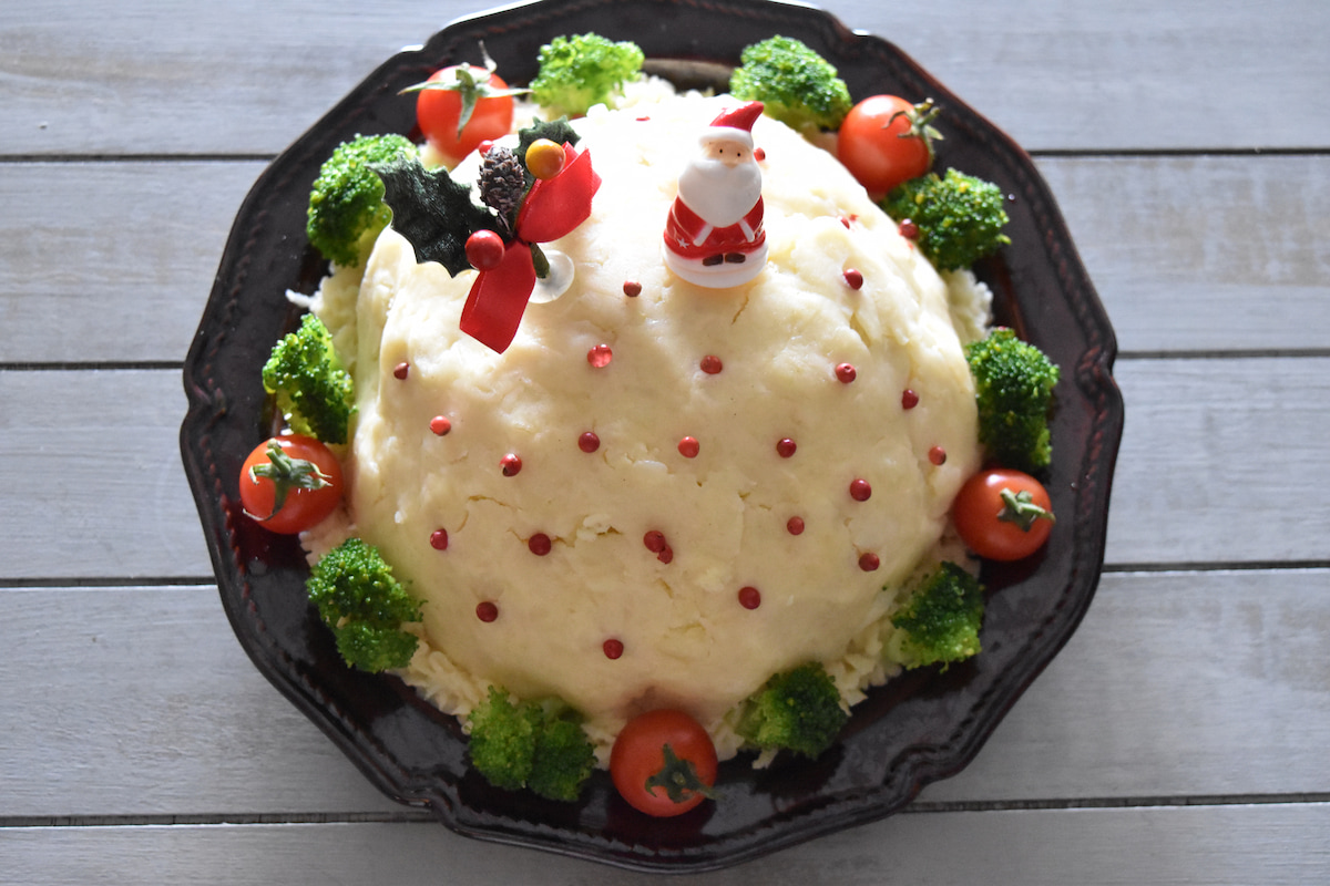 サンドイッチをひっくり返して皿に盛り付け、マッシュポテトを全体に塗り、ピンクペパーやブロッコリーを飾る（ドームサンドイッチ）