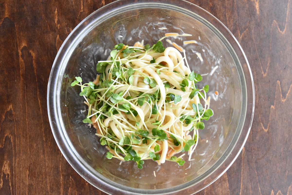 混ぜ合わせたうどんにカイワレを混ぜる(なめたけバターうどん)