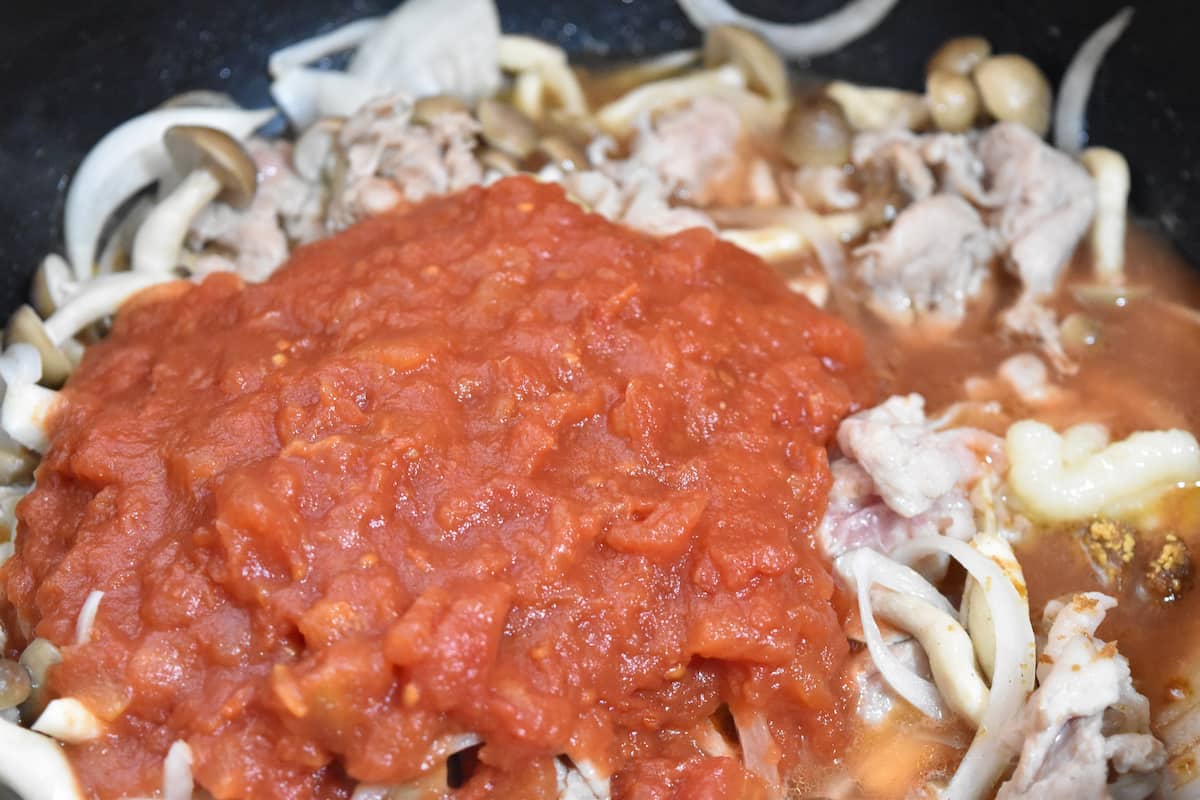 トマト缶や調味料を加える(豚こまとしめじのガーリックバタートマト炒め)